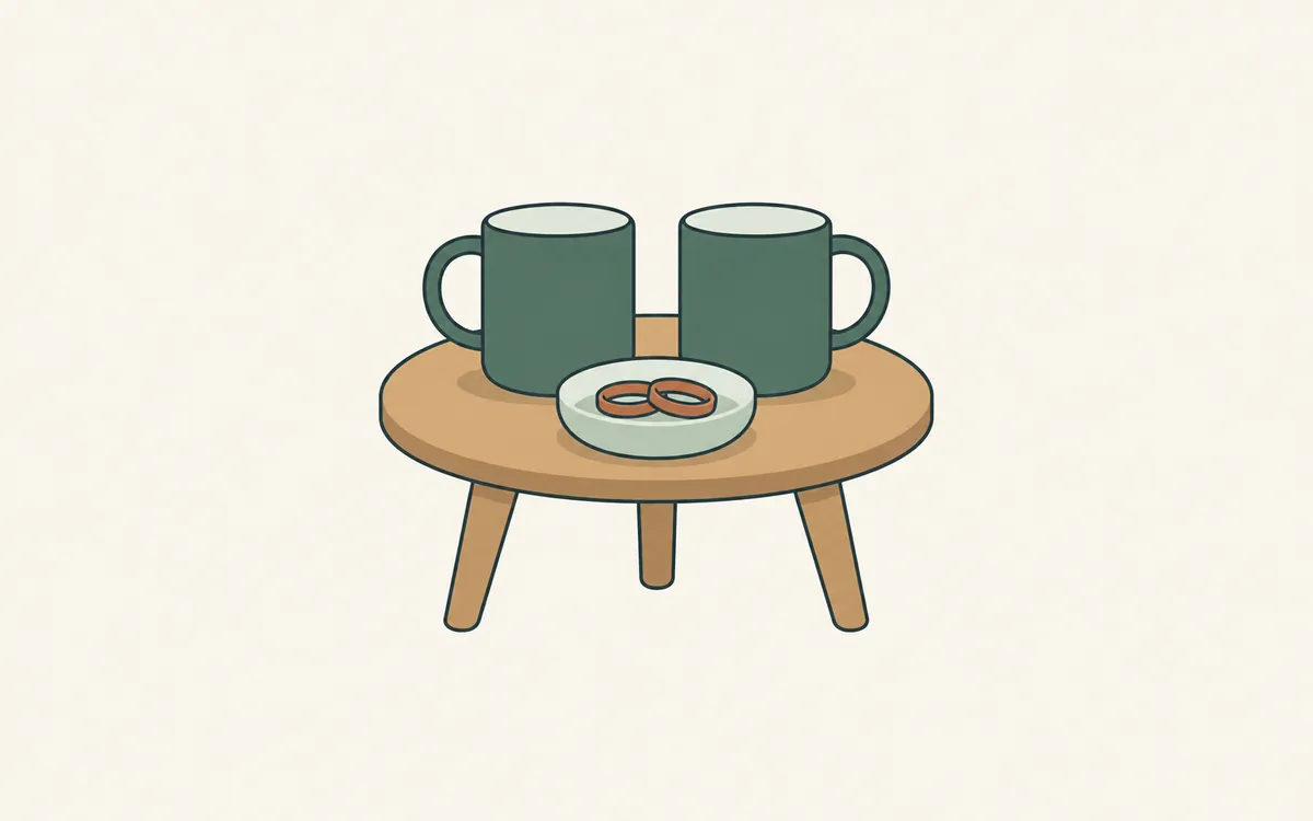 Two identical mugs on a small round table, with two matching rings in a dish.
